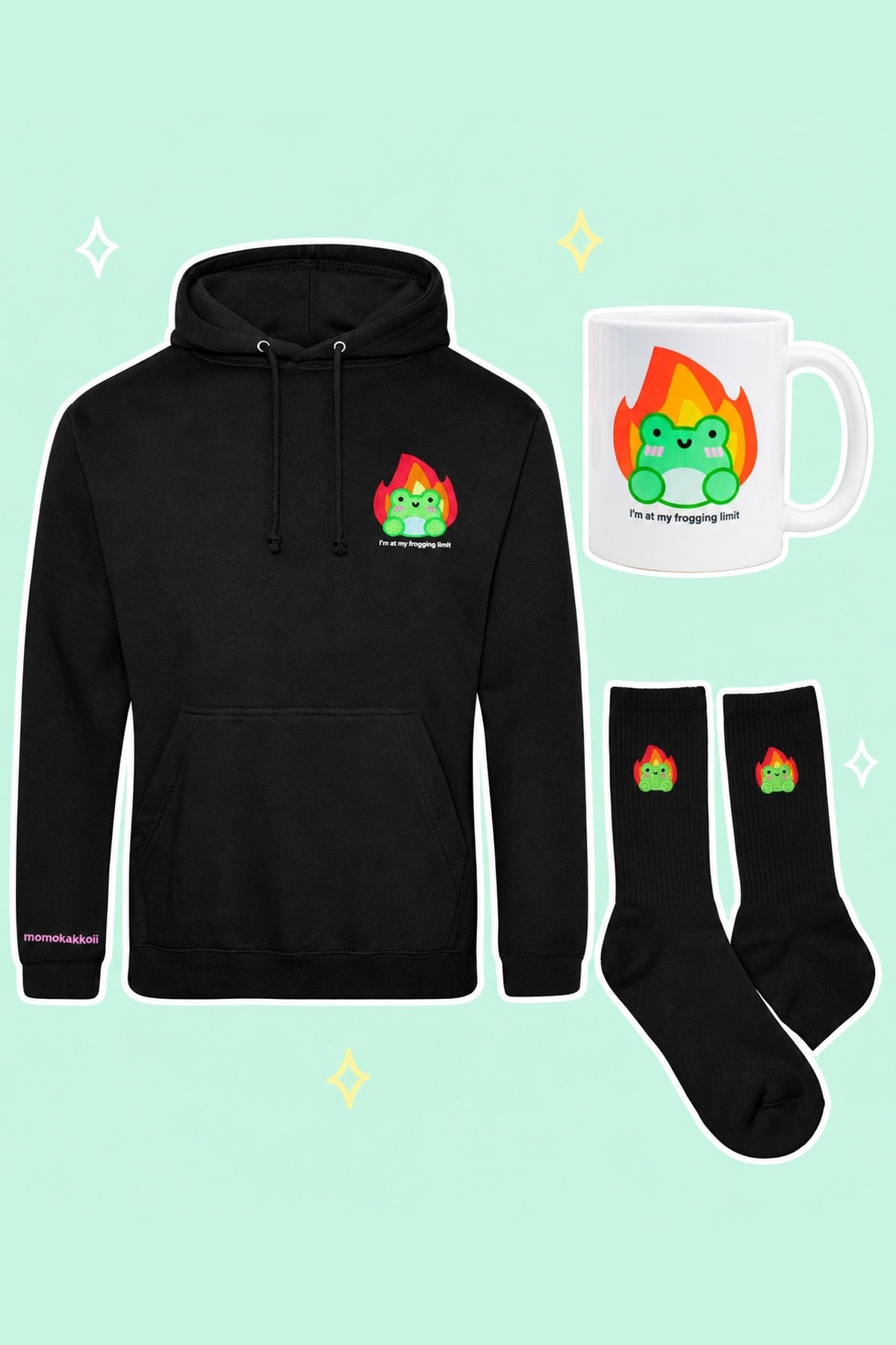 At My Frogging Limit Survival Kit: one black I'm At My Frogging Limit embroidered hoodie, one matching white ceramic mug, one pair black Albert In Flames embroidered socks, on a simple pastel background with white outlines and small sparkles.