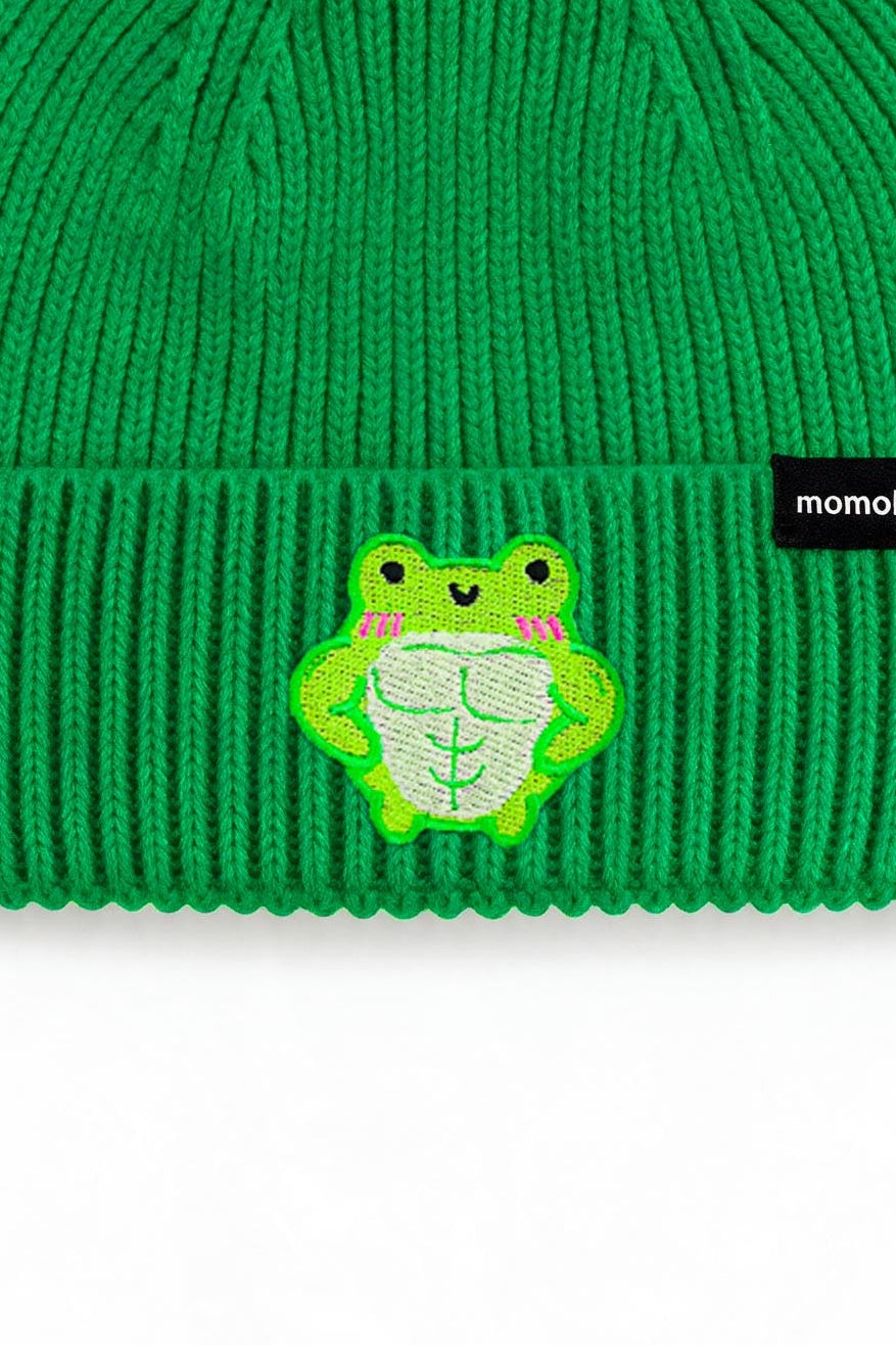 A bright green ribbed knit beanie hat featuring a small embroidered frog patch on the front cuff and a black brand tag that reads 'momikakkoi'.