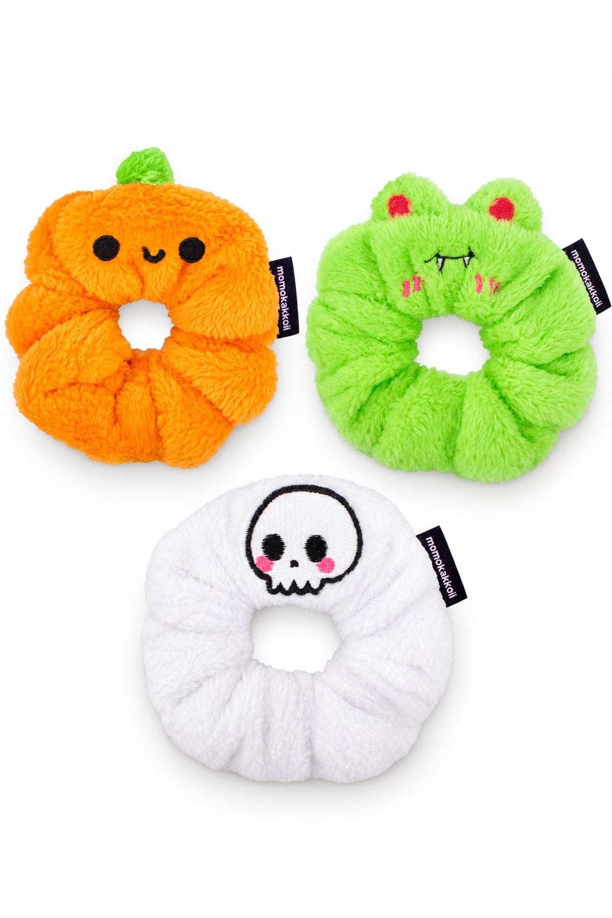 White-background product arrangement: one orange Patch the Pumpkin scrunchie with cute round black eyes and curved smile (NOT jack-o-lantern), one lime green Vampire Albert scrunchie with red eyes and fangs, one white Cute Skull scrunchie.